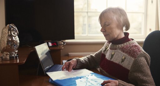 Erica, who lives with chronic lymphocytic leukaemia (CLL), sits at her desk, filling paper into a folder.