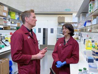 Female researcher showing a man things in a lab.