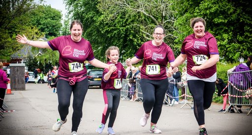 Four people take part in the Bromsgrove Fun Run, smiling and wearing their Blood Cancer UK T-shirts and runner numbers.