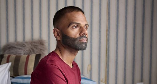 A man sits on the side of a bed thinking.