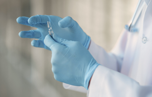 A doctor with blue gloves holding a medical implement.