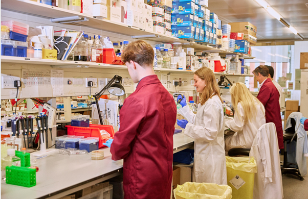 Researchers in a lab smiling in lab coats working