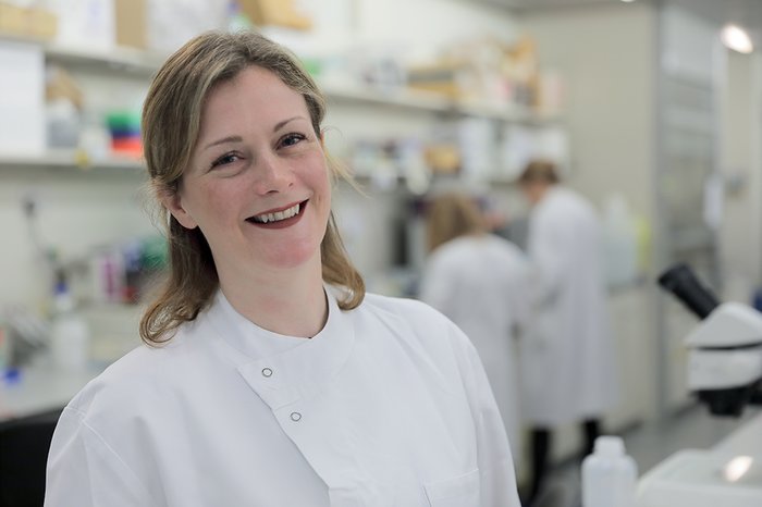 Dr Beth Payne standing in the lab smiling