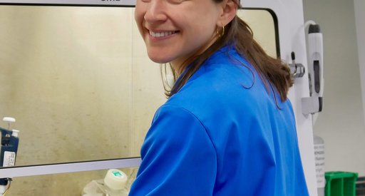 A lady wearing a blue lab coat smiling at the camera.