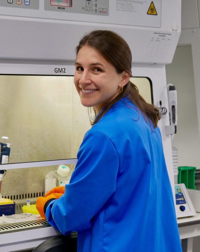 A lady wearing a blue lab coat smiling at the camera.