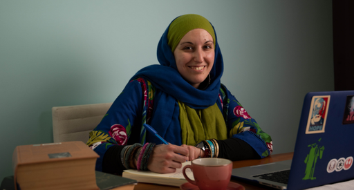 Federica Nardella, blood cancer patient, sat at a desk writing in a notebook in front of her laptop.