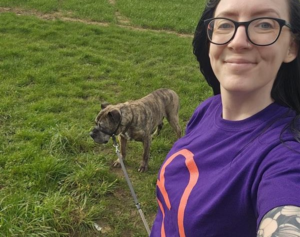 Female taking a selfie, wearing a Blood Cancer UK t-shirt with her dog in the background