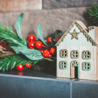 Close up photo of a Christmas display, with holly leaves and a small model wooden house.