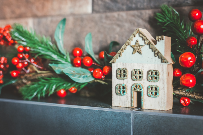 Close up photo of a Christmas display, with holly leaves and a small model wooden house.