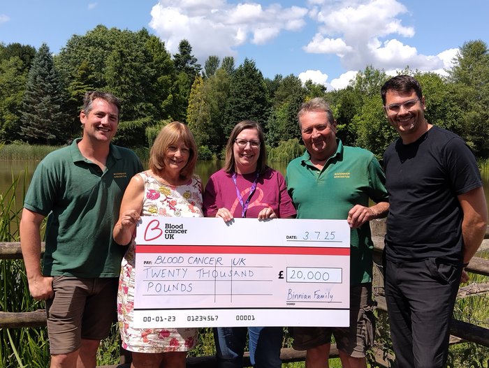People smiling holding a check in front of trees