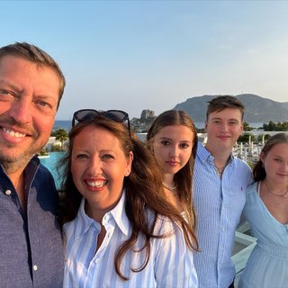 Matthew Wilson stands smiling with his family on a sunny evening in Summer.