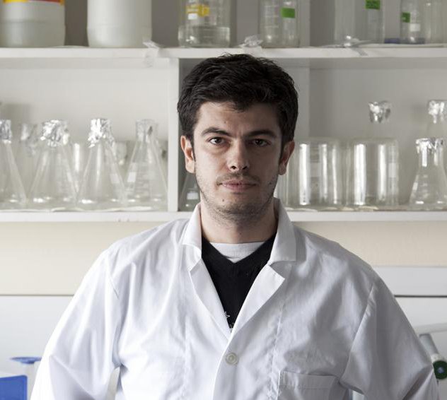 A photo of a man in a lab wearing a white lab coat.