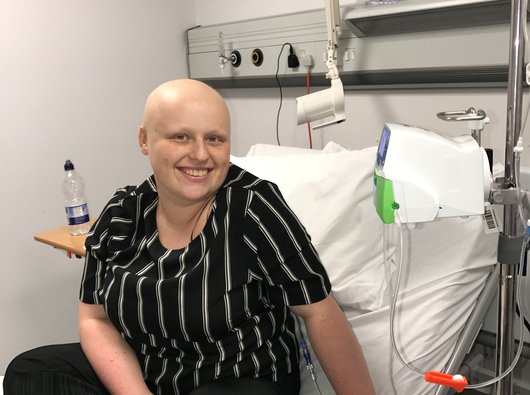 Women with bald head from cancer treatment smiling on hospital bed