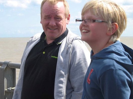 Jake Moules, Blood Cancer UK supporter stood by the sea with his stepdad Paul.