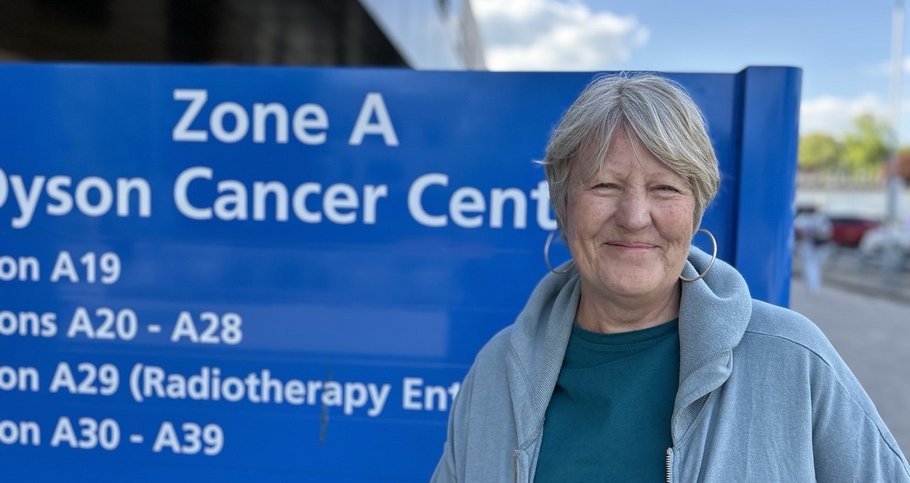 Jo stood by the treatment centre sign smiling to the camera