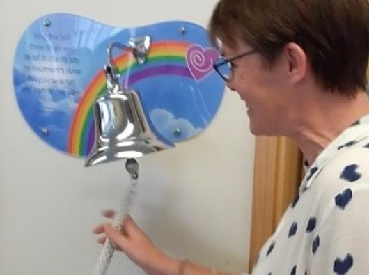 Jo, blood cancer patient, ringing the end of treatment bell in the hospital.