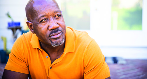 An older middle-aged Black man in an orange shirt.