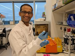 Dr Batta stood working in the lab smiling at the camera.