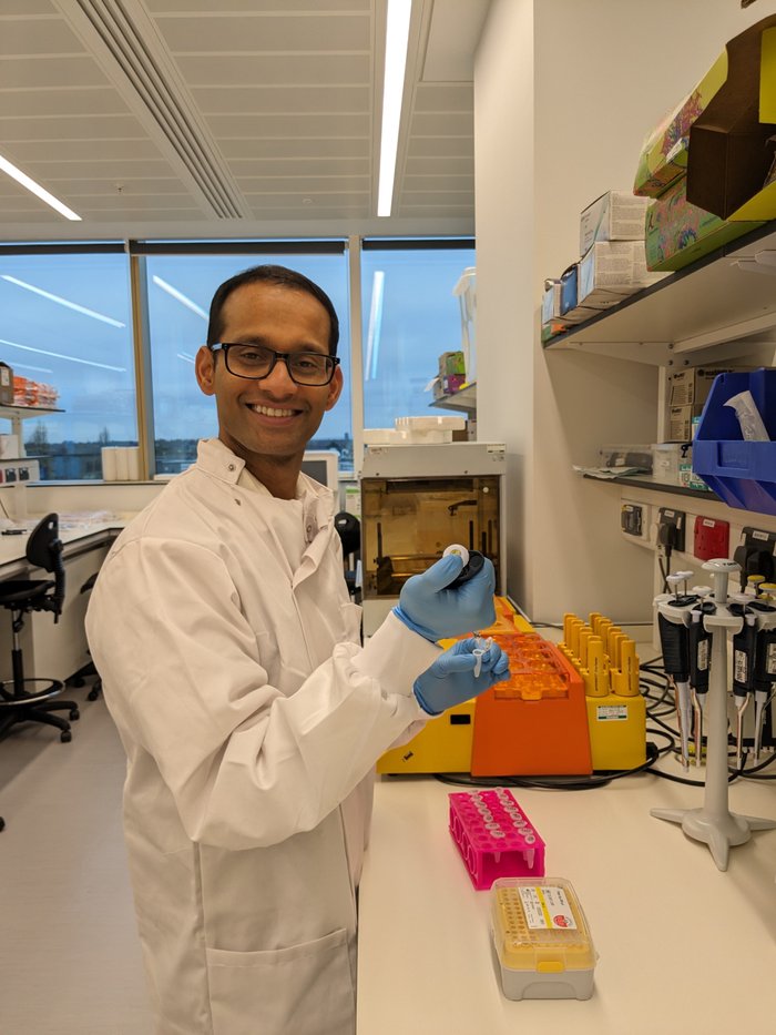 Dr Batta stood working in the lab smiling at the camera.