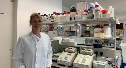 Dr Kristina Kirschner stood in the lab wearing a lab coat smiling at the camera.