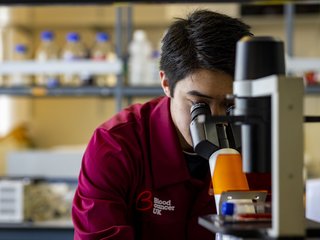 Researcher looking into a microscope