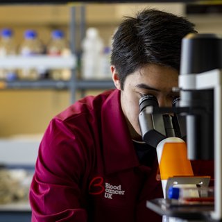 Researcher looking into a microscope