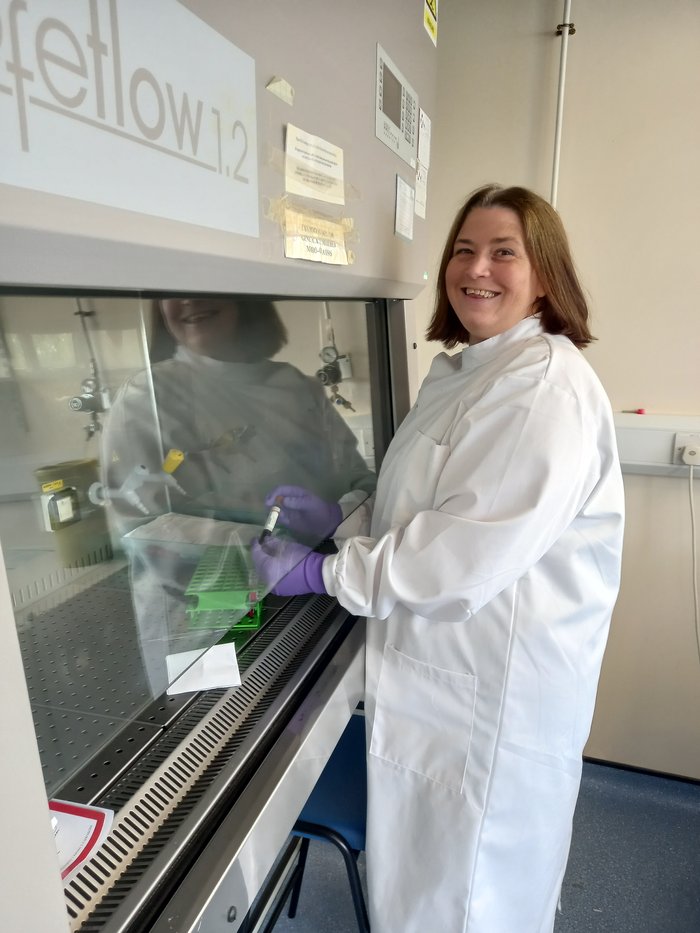 Professor Lesley Anderson stood up smiling as she is working on her research in the lab.