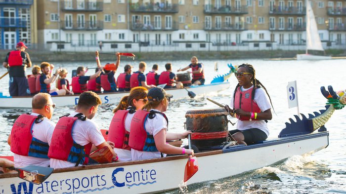 A rowing team sitting in their boat, wearing red life jackets.