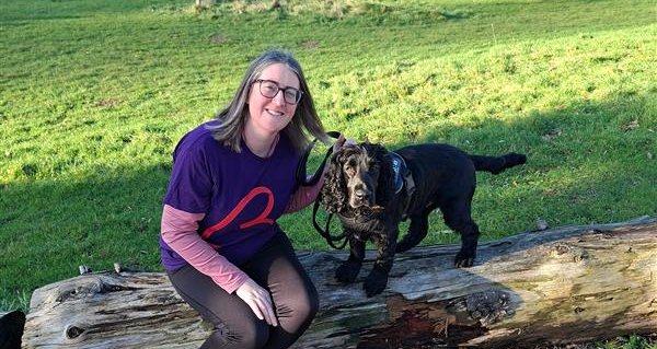 Image of Lorna sat on a log with her dog