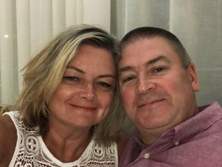 A middle aged couple pose for a photo together indoors