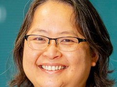 Headshot of a lady with short dark hair wearing glasses and smiling at the camera.