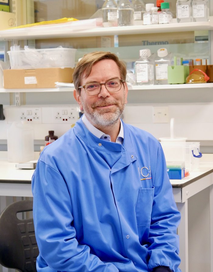 A man wearing glasses and a blue lab coat.