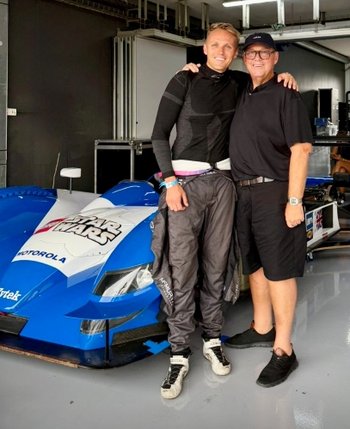 A photo of Chily and his son Max standing beside a racing car