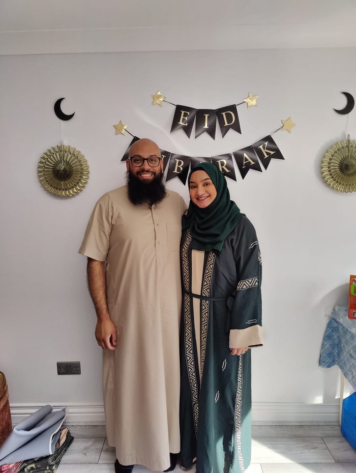 Nabeela and a man, standing in front of a sign saying 'Eid Mubarak'