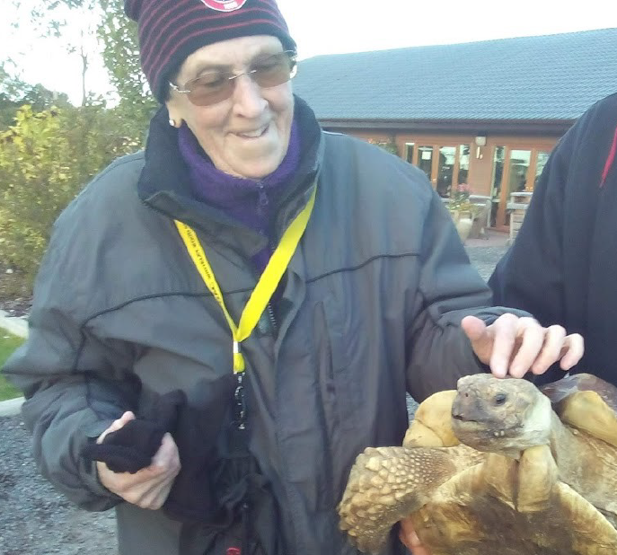 Pat, who lives with Classical Hodgkin lymphoma, pets a tortoise outside.