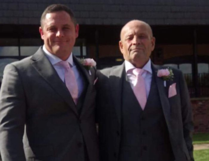 Two men pose together at a wedding wearing magic suits.