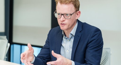 A man in a suit sat at a table explaining his research to others