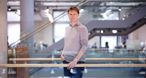 Professor Pavel Tolar stood on a glass walkway in a grand university building looking at the camera