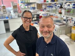 Professor Tooze sat in his lab smiling with his colleague