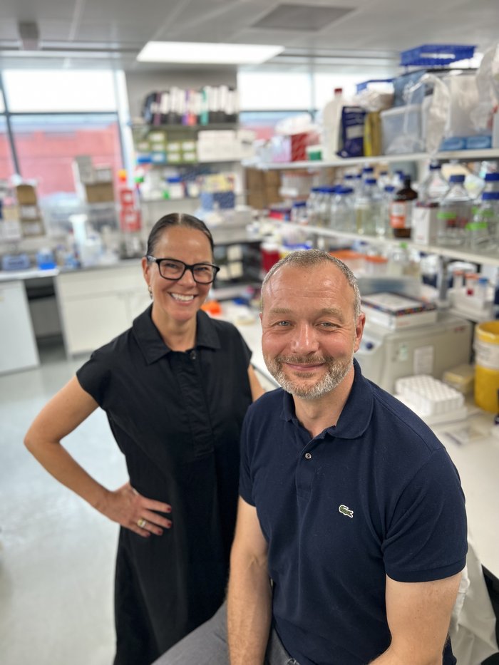 Professor Tooze sat in his lab smiling with his colleague