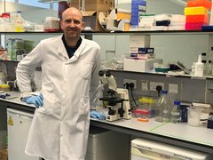 Professor Helgason standing in the lab wearing his lab coat