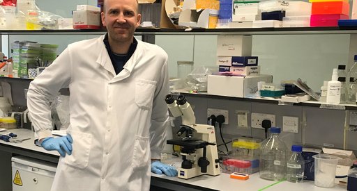 Professor Helgason standing in the lab wearing his lab coat