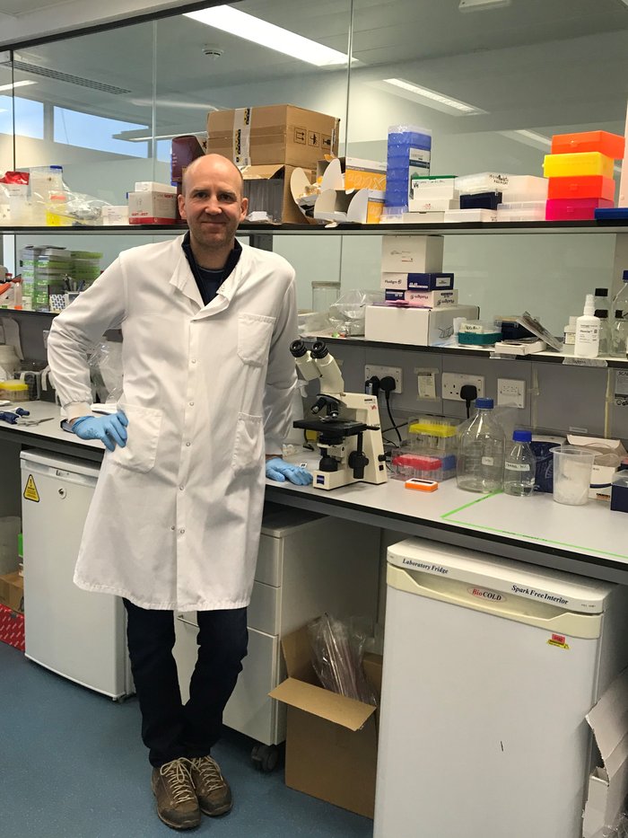 Professor Helgason standing in the lab wearing his lab coat