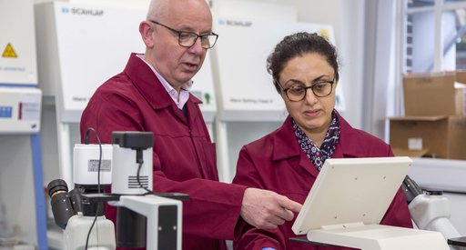 Two researchers stand in a laboratory. They are examining the screen of a piece of equipment.