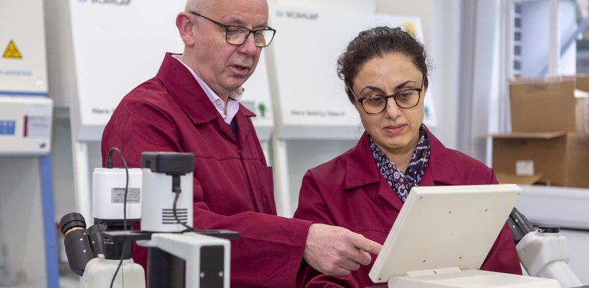 Two researchers stand in a laboratory. They are examining the screen of a piece of equipment.