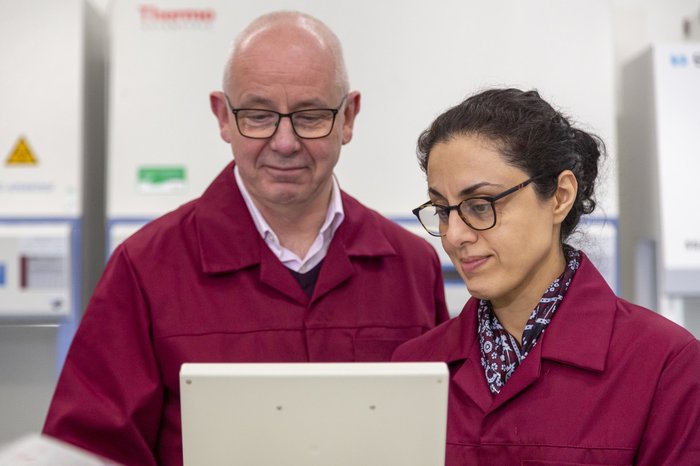 Two Blood Cancer UK Researchers standing side-by-side looking at a screen together.