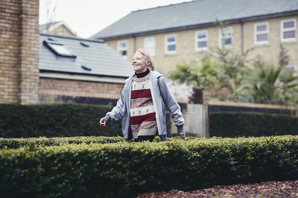 Erica, who has chronic lymphocytic leukaemia (CLL) walking down a path between two bushes.