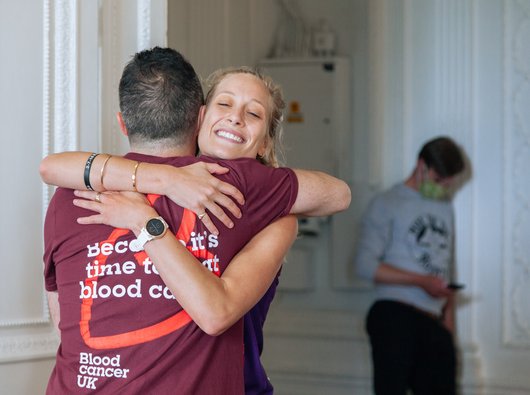 Two supporters hug wearing Blood Cancer UK t-shirts