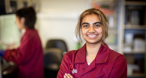 A researcher smiles at the camera, wearing a burgundy Blood Cancer UK jacket