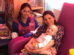 An image of a child battling blood cancer, smiling with her parents.